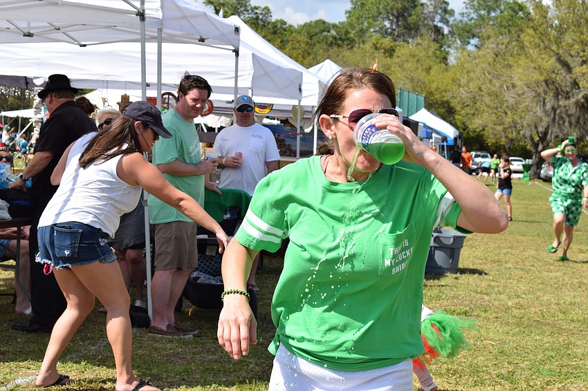 Amy Walczak, of Bradenton, chugs a green beer in the midst of the relay race at the festival.