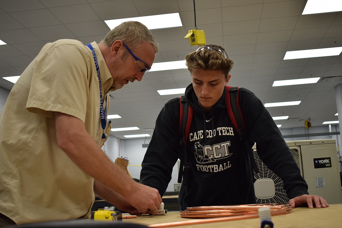MTC HVAC student explains to Braden River Highschool freshman Justin Hilts how to cut a length of pipe.