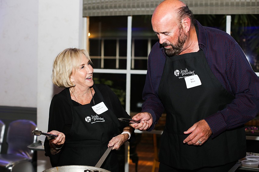 Angie Reichheld and Kyle Doan laugh as they cook their dishes.