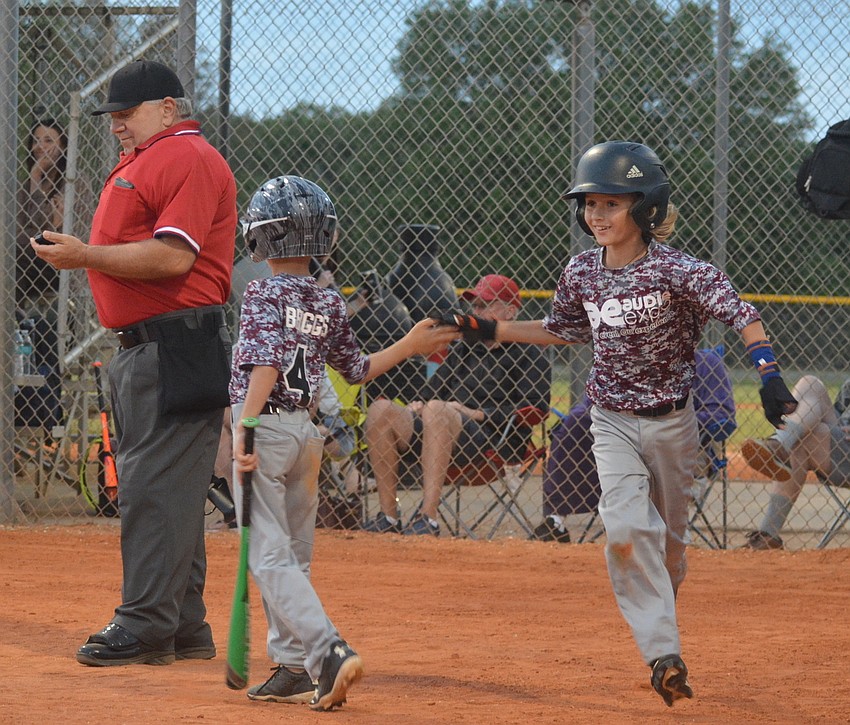 Landon Marazon gets a high five after scoring during Lakewood Ranch Little League play.