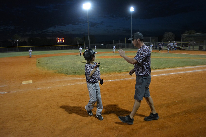 Landon Marazon receives congratulations from his manager, Matt Martin, after he beat out an infield hit.