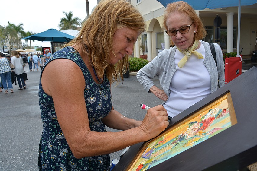 Artist DAwn Normali, of Colorado, touches up the frame of a painting purchased by Lakewood Ranch resident Judy Marcelli.