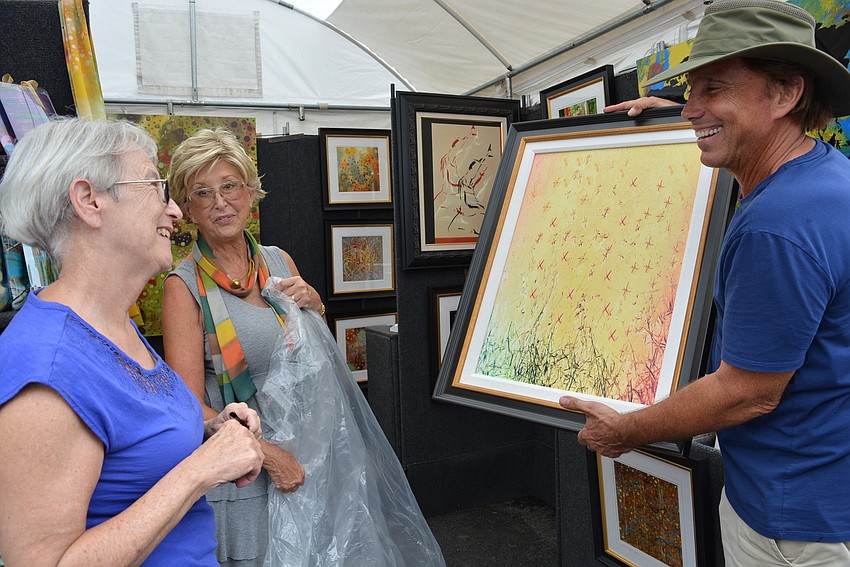East County's Candis Smith loves the painting she purchased from artist Paul Laoria, pictured with his wife, Gail Laoria, behind. 