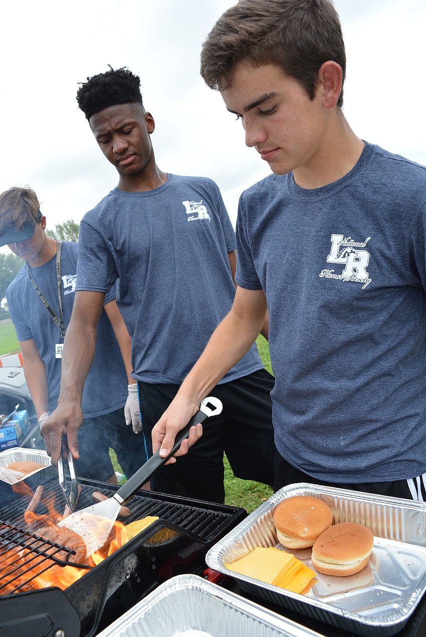 Senior Alex Thompson, front, with Joshua Young, behind, dish up hot dogs and hamburgers to raise funds for the National Honor Society.