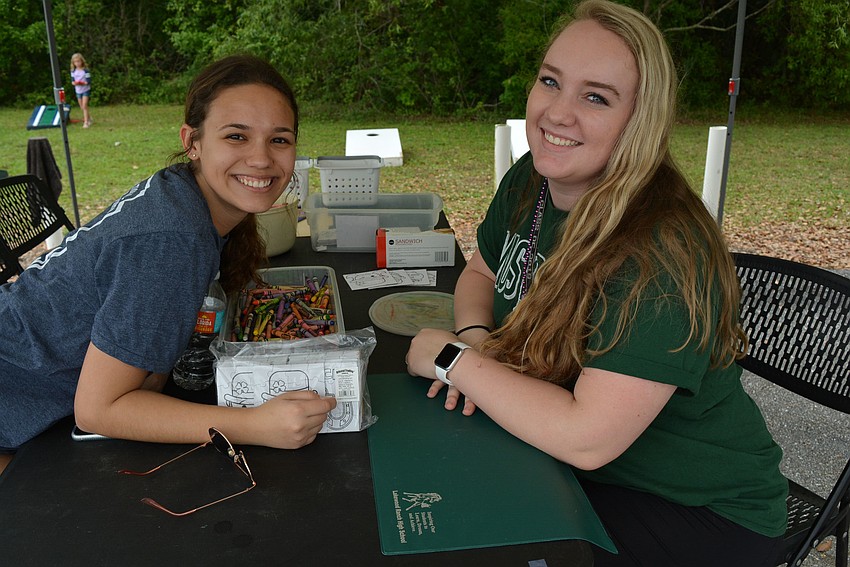Bella Sellmer and Angela Baldino man a coloring booth, as well as games of corn hole, to raise funds for the Quill and Scroll club.