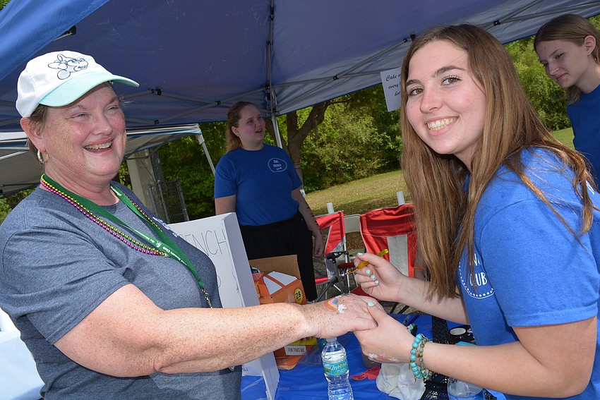 National Honor Society adviser and event organizer Mary Ellen Eskett gets a rainbow painted on her hand by Ava Botko.