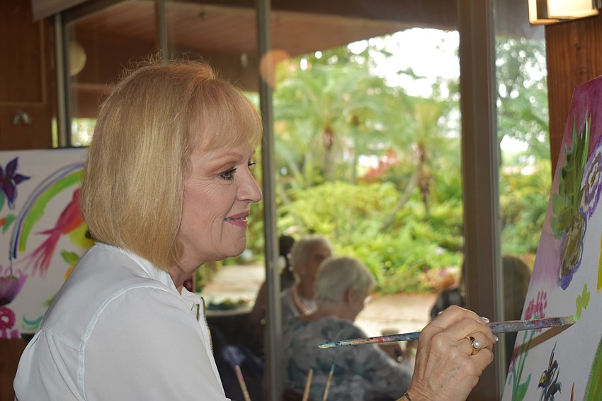 Dodie Mash paints on the community art at the lunch.