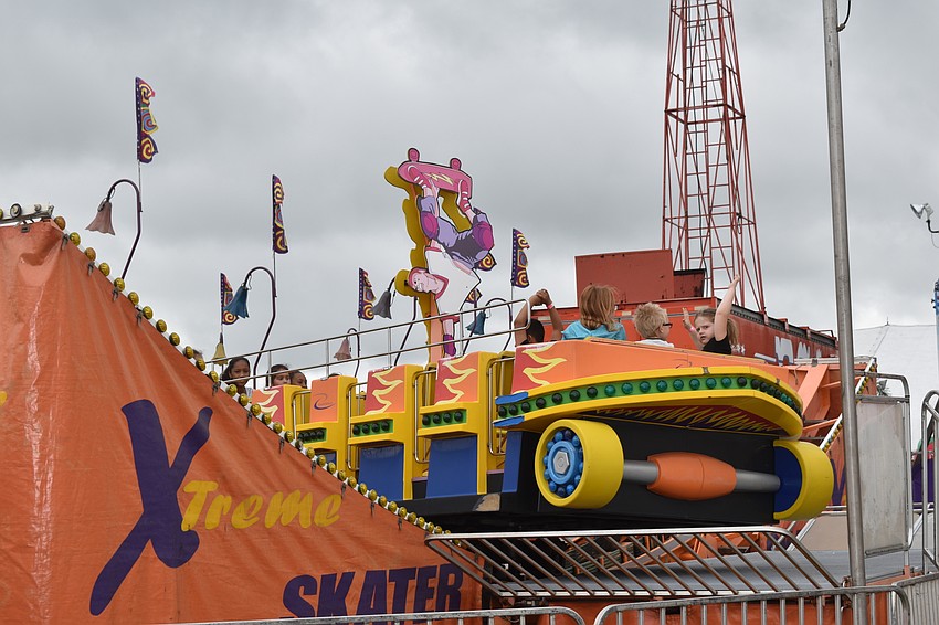 Kids threw their hands up in excitement on rides, like this one shaped like a skateboard.