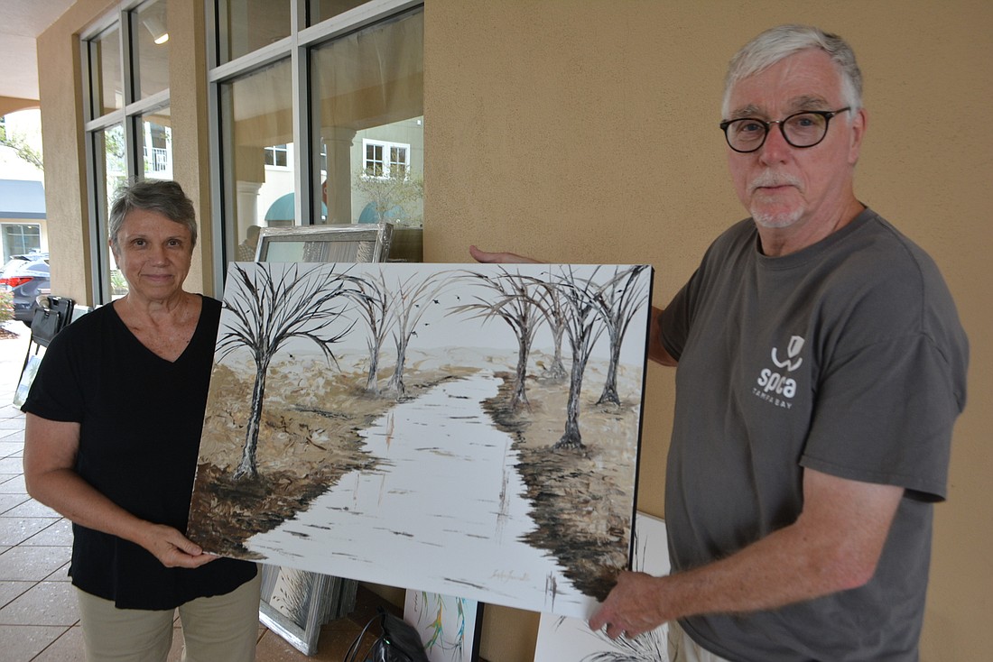 Sue Ann Iannello and her husband, Frank, carry out one of her paintings from J&J Gallery, which closed.
