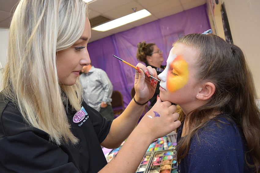 Childlike Productions' Brianna Raia paints a rainbow tiger face on 6-year-old Kayleen Zieschang.
