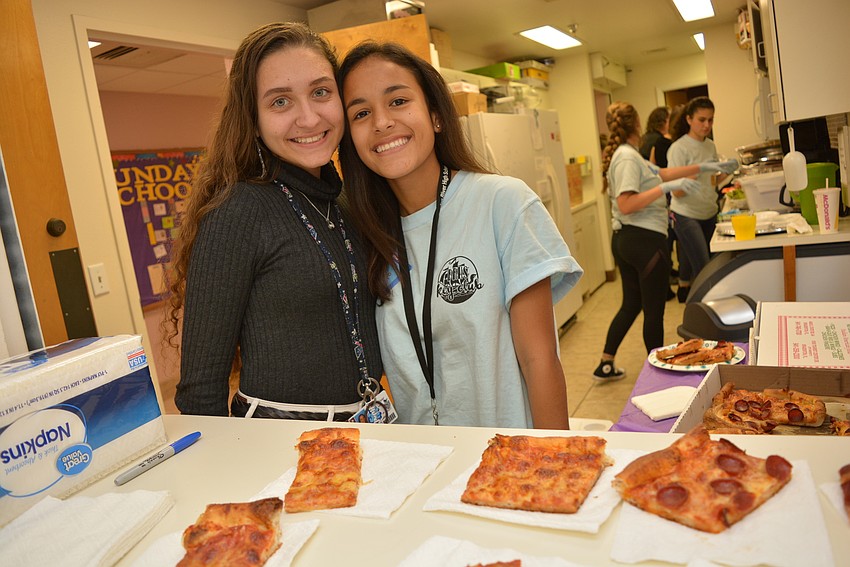 Braden River High School Key Club volunteers Alexandra Stoilova and Melanie Herrera have the important job of serving pizza to children in the 