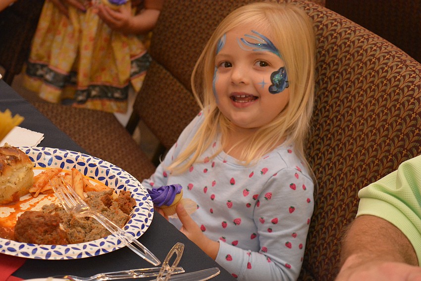 Three-year-old Charlotte Gebhart, a student at All God's Children,  feasts on dinner with family.