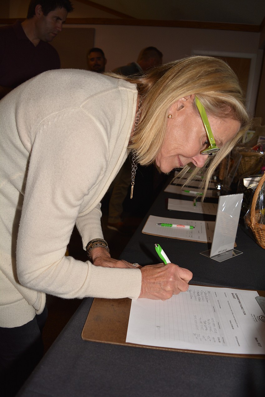 Sarasota's Mary Uihlein bids on a silent auction item to support the school. Her grandson, 3-year-old James A. Uihlein, attends.