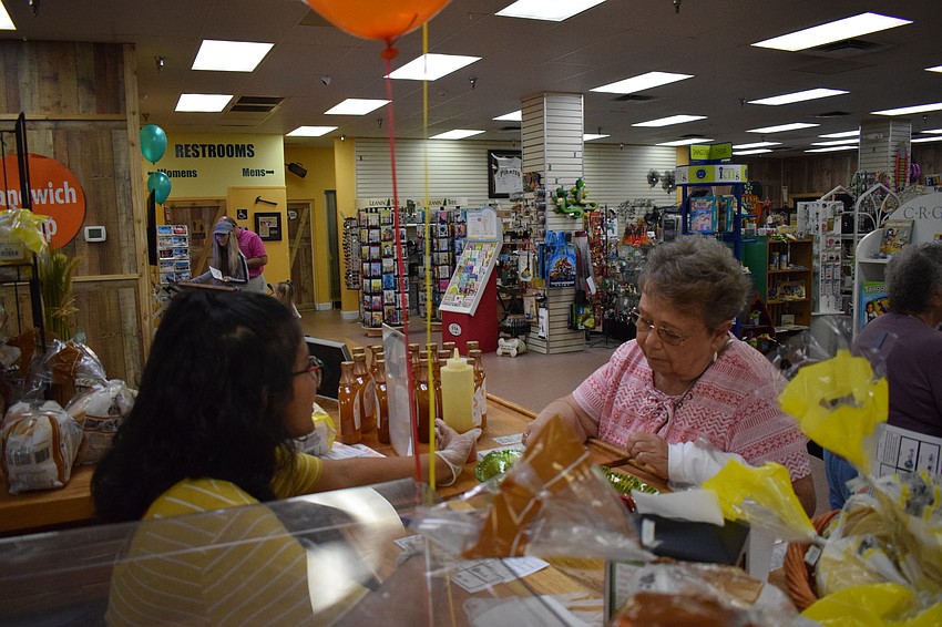 Linda Racine of West Winds enjoys a sample of orange syrup served by volunteer Deeya Bhatt, a freshman at Southeast High School.