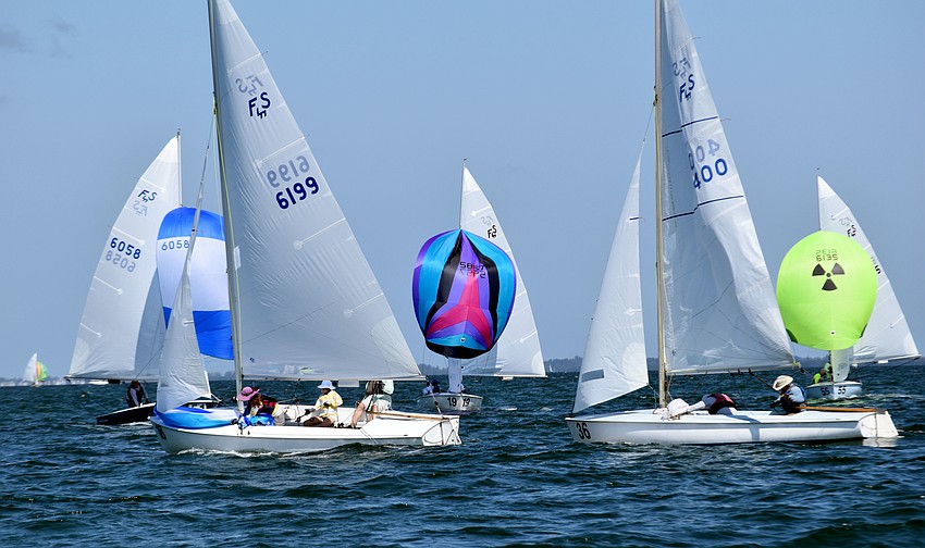While the sailors' boats are all the same, their spinnakers are a variety of colors.