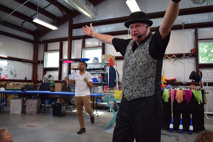 Magician Jeff Lovett works the crowd while Azam Rangoonwala balances two plates while standing on one foot.
