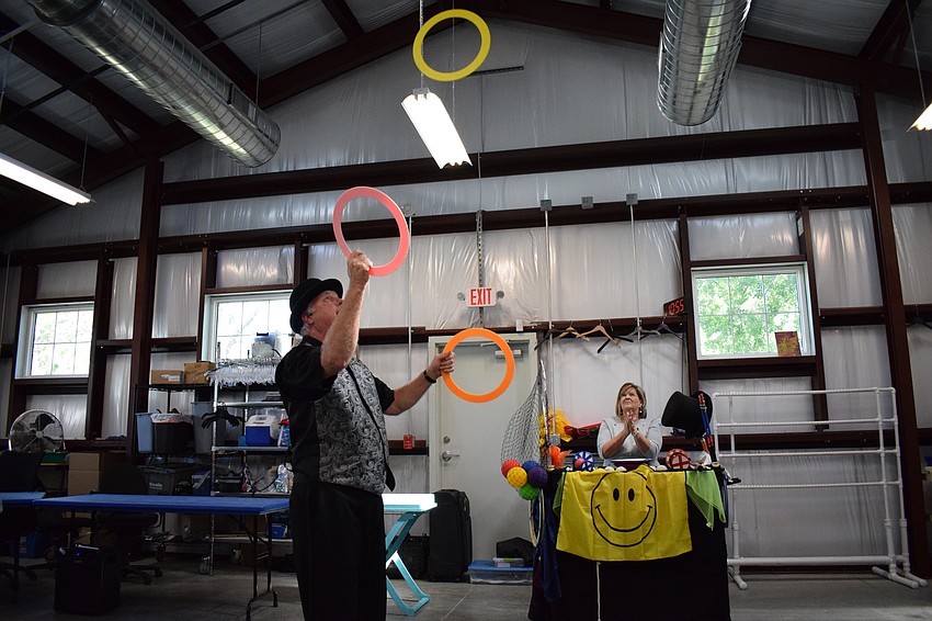 Jeff Lovett — who goes by Jeff the Juggler — juggles rings while his wife, Lori Lovett, looks on.