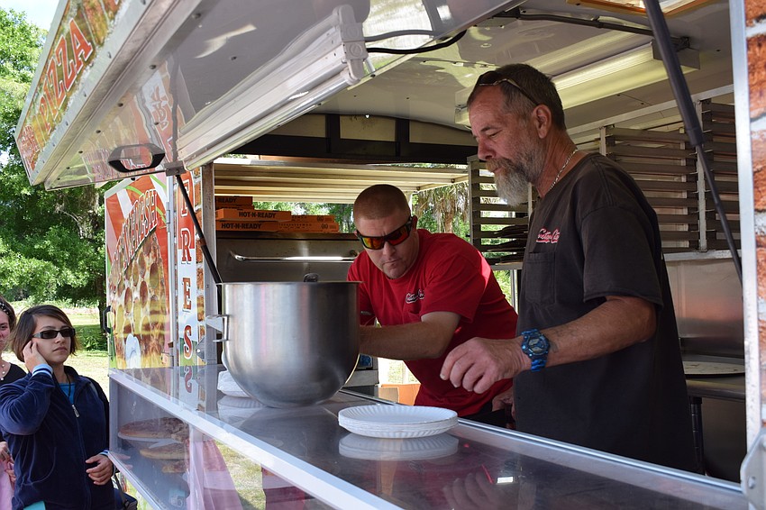 Corey Volosin and Hank Fish, of Custom Catering, serve up slices of pizza.