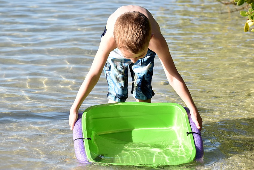 Chase Henderson drags his tub into Sarasota Bay. Campers used the bins as a holding spot for any marine life they found.