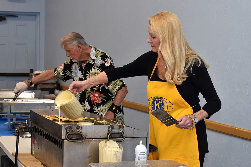 Ed Krepela and Susan Phillips make pancakes and serve sausage to guests.