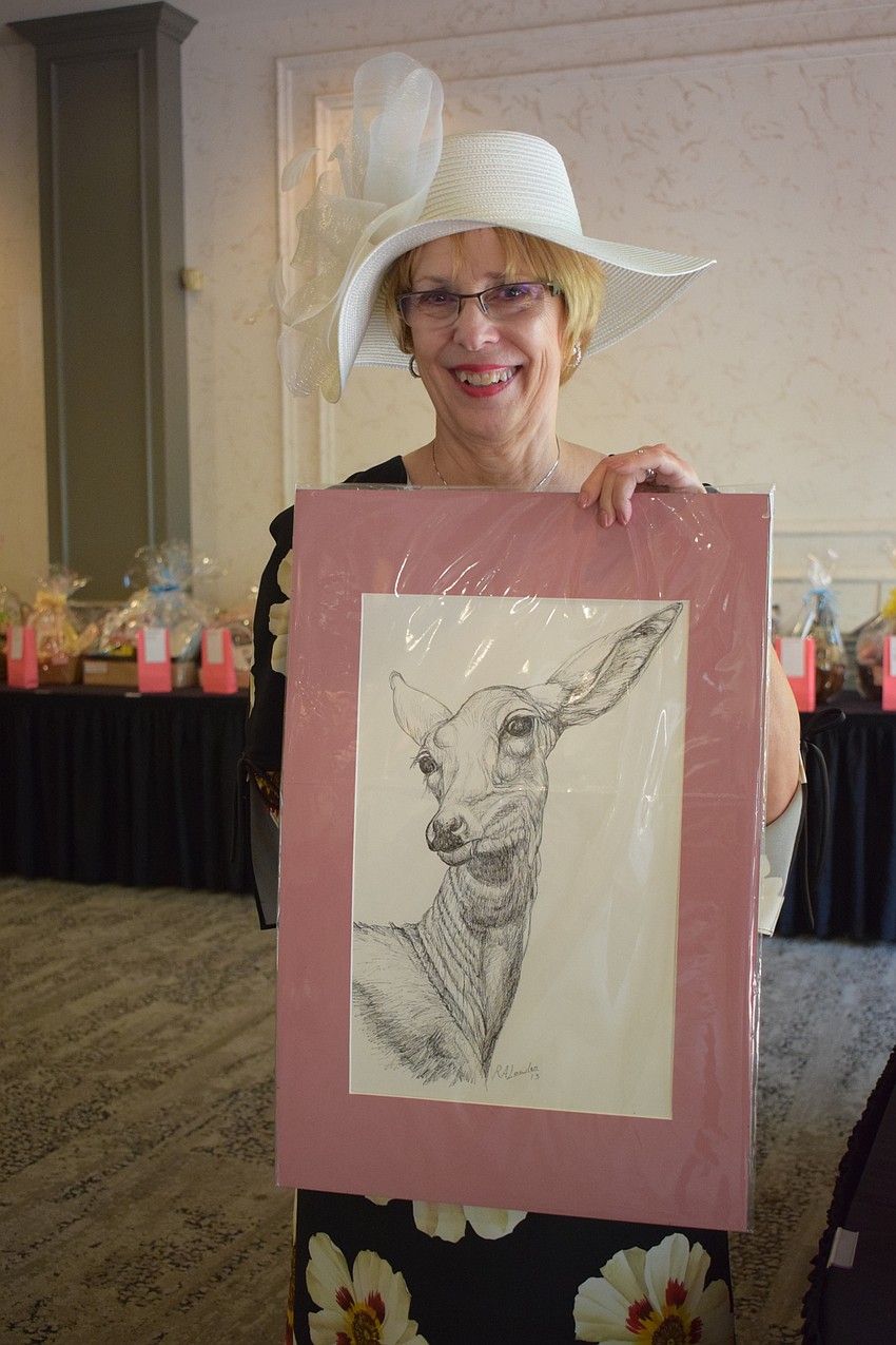 Ann King was particularly proud of her hat, but she also is pleased with the artwork she won as a door prize.