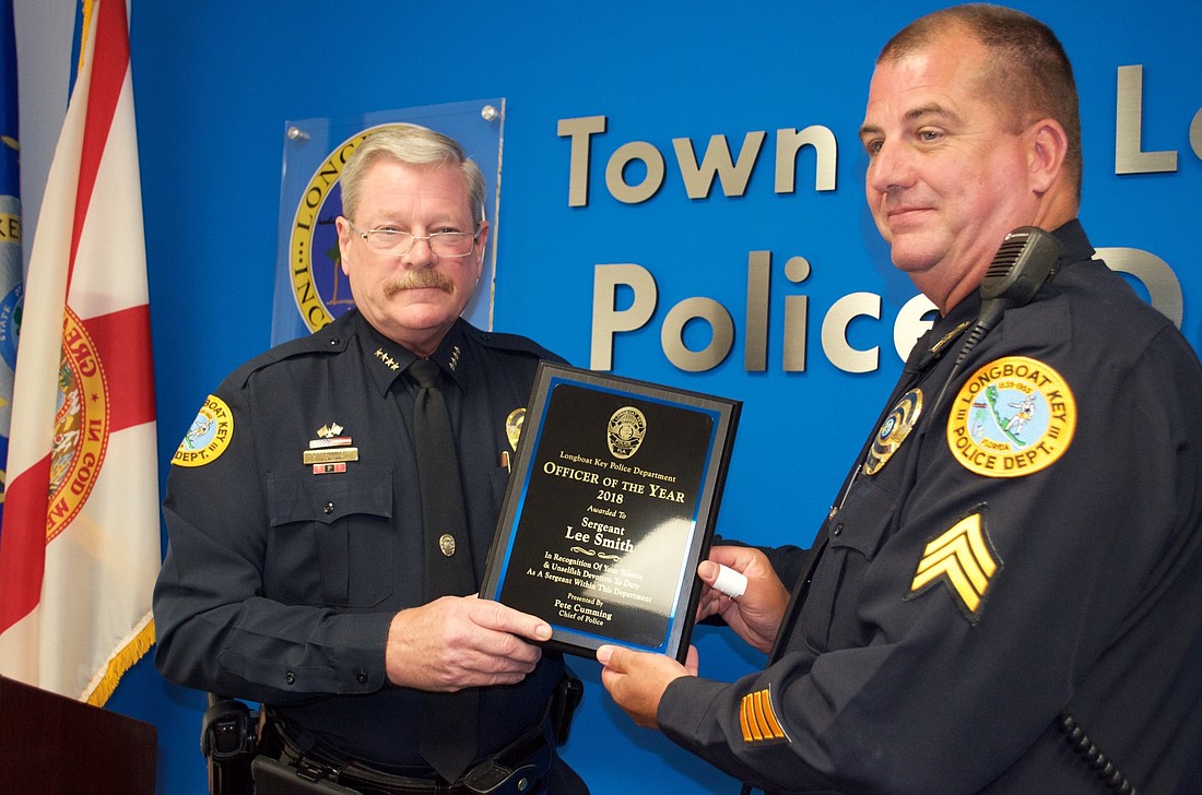 Longboat Key Police Chief Pete Cumming hands the Officer of the Year plaque to Sgt. Lee Smith.