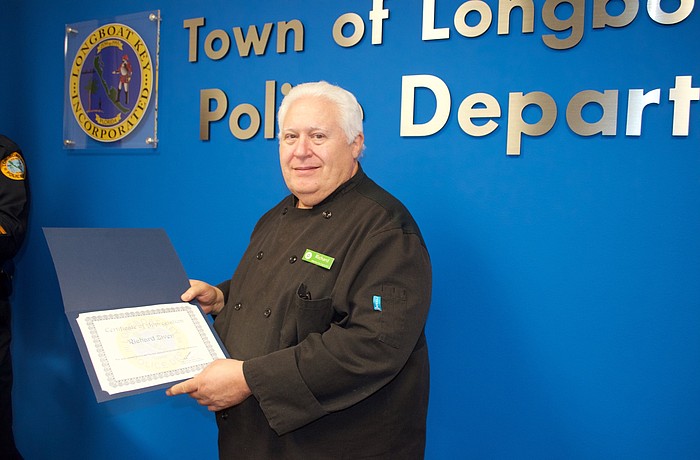 Publix employee Richard Ziven accepts a certificate from the Longboat Key Police Department for turning in a lost money clip.