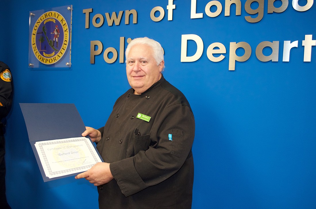 Publix employee Richard Ziven accepts a certificate from the Longboat Key Police Department for turning in a lost money clip.