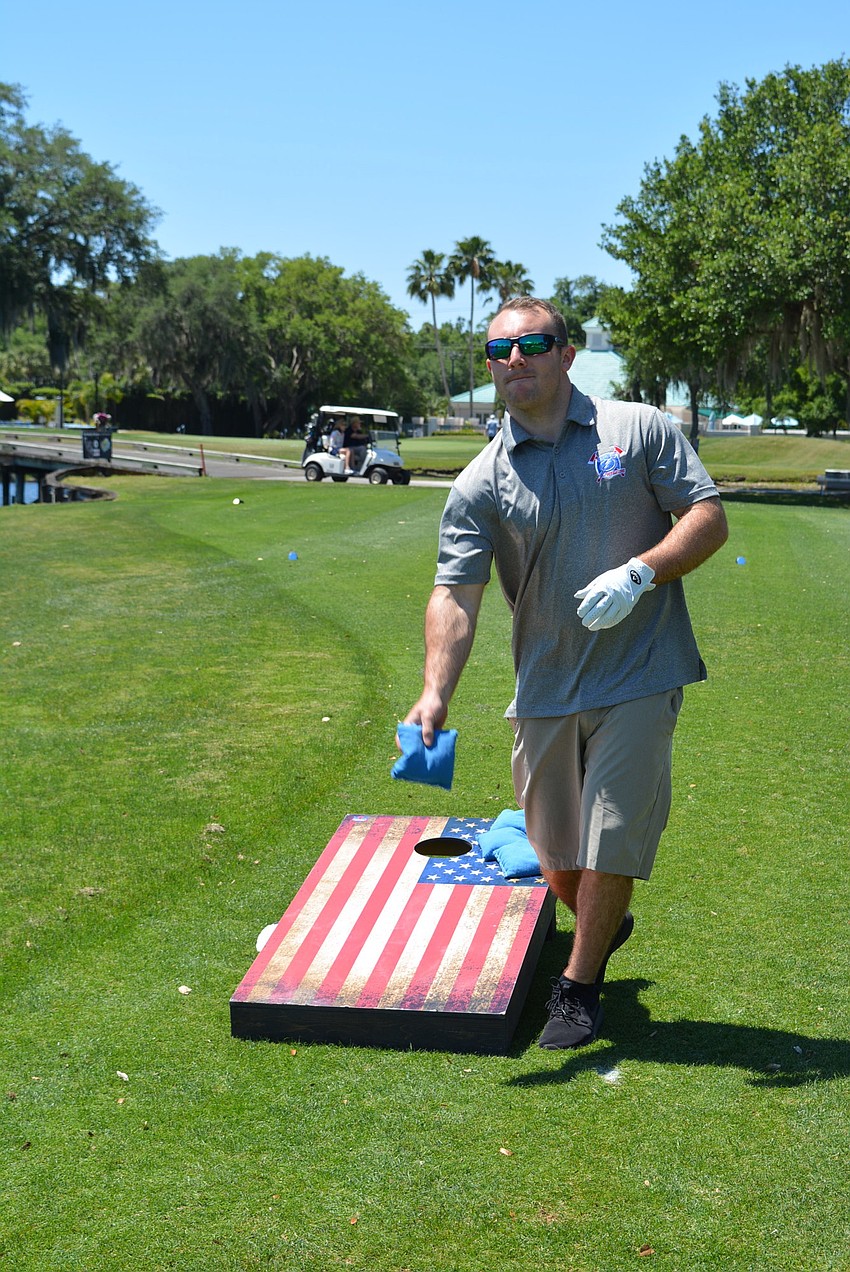 Ellenton's Timothy Ball tries his hand at corn hole at Hole 10, where Veterans Air was a sponsor.