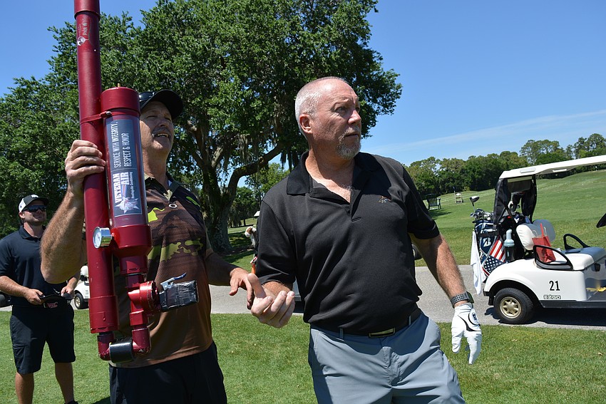 Jeff Ball opts for shooting his ball with an air gun rather than hitting it on a special Hole 10 challenge. Air Golf Pro Launcher Team Challenger owner Robert Block, left, watches.