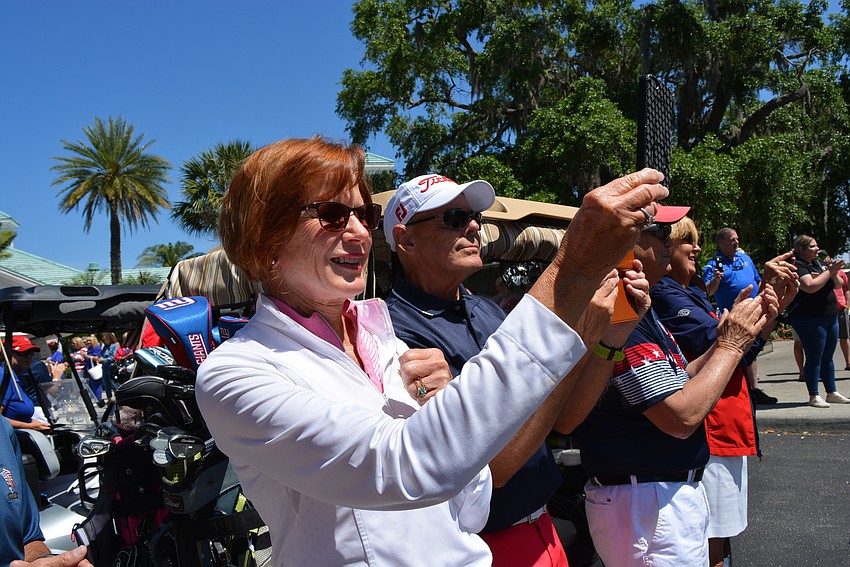 Irene Ward, with her husband, Brian, records the opening parade of motorcycles with her cell phone.
