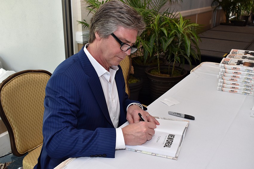 Tim Ortman signs a copy of his book for Library Foundation President Isabel Norton.