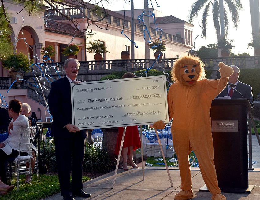 Florida State University President John Thrasher holds up a ceremonial check worth $101,330,000 with Ringling mascot Reuben.