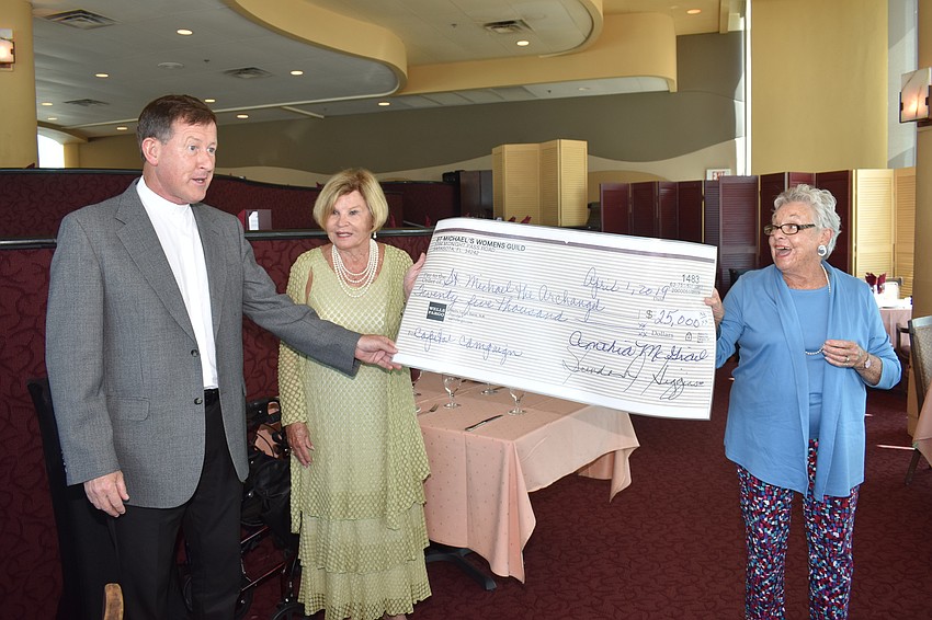Fr. Michael Cannon is presented the check from Linda Conway ad Kathy Caltagirone