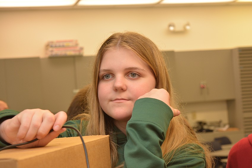 Thirteen-year-old Lauren Dalton uses a scope in a box to try to figure out its contents.