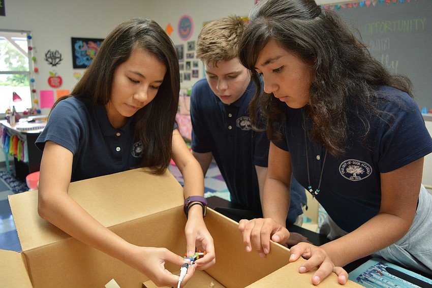 Julieann Shapiro, 13, connects magnetic circuits. After the box encloses the circuits, Julieann and her partners, Mason Alexander and Sara Chinnici,  try to hit a sensor with a laser and make a light turn on.