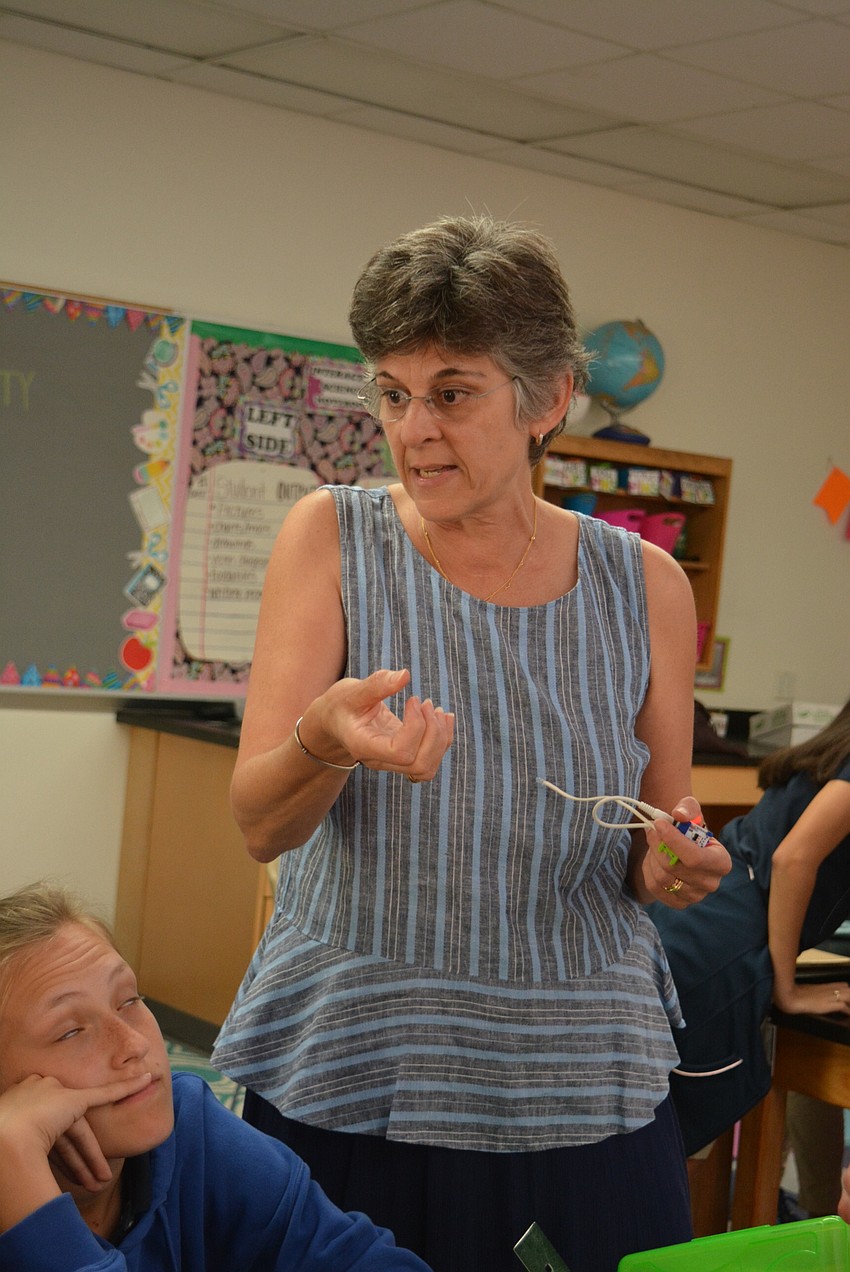 Teacher Joanne Barrett talks with students about adding a beeper for their activity to make it more like the game 