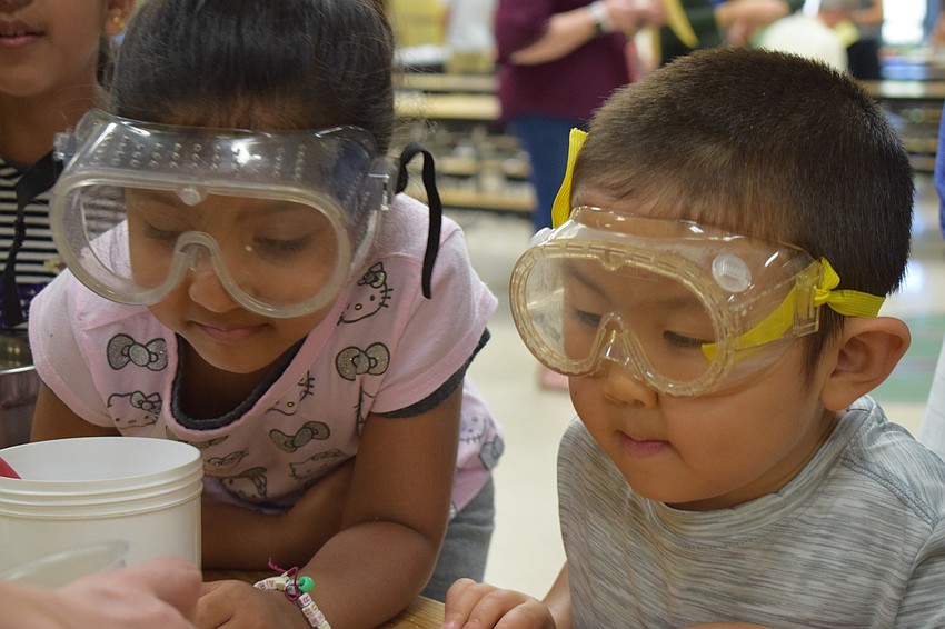 Eric Zhang and Aaliya Mittal, both in Pre-K, watch a demonstration of what happens when you mix baking soda and vinegar — bubbles.
