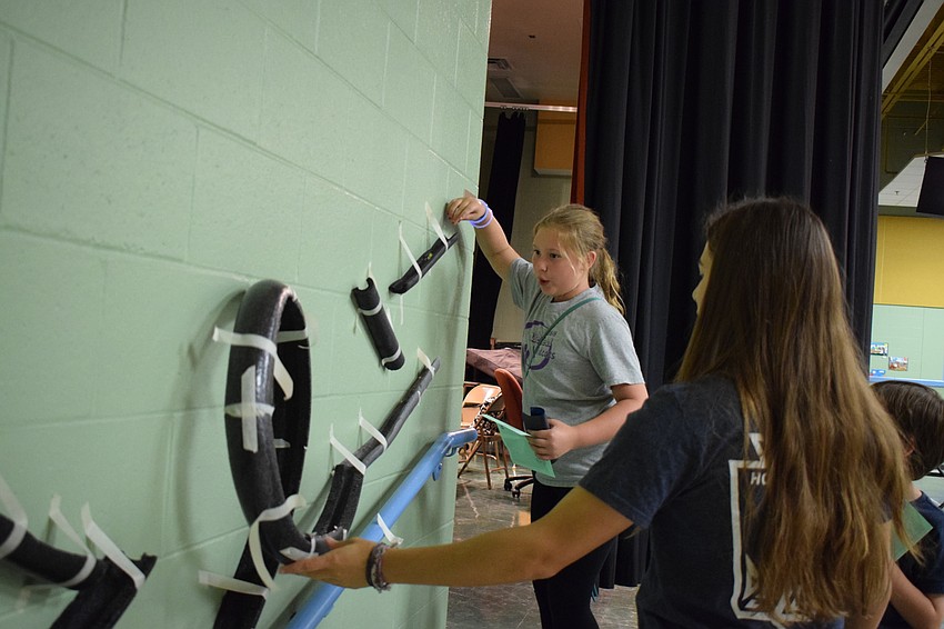 Laurayne Bond, a fifth grader, watches as a marble rolls down the track.