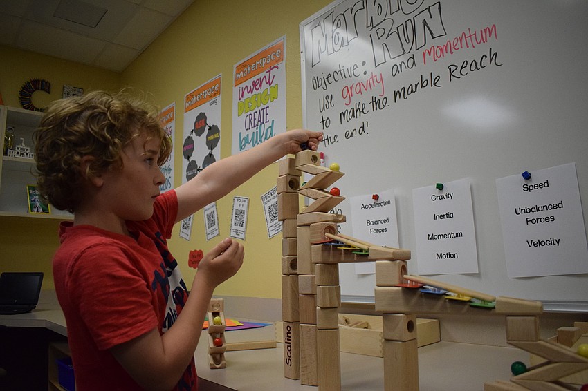 Austyn Murphy adjusts his marble run, trying to make everything play just right.