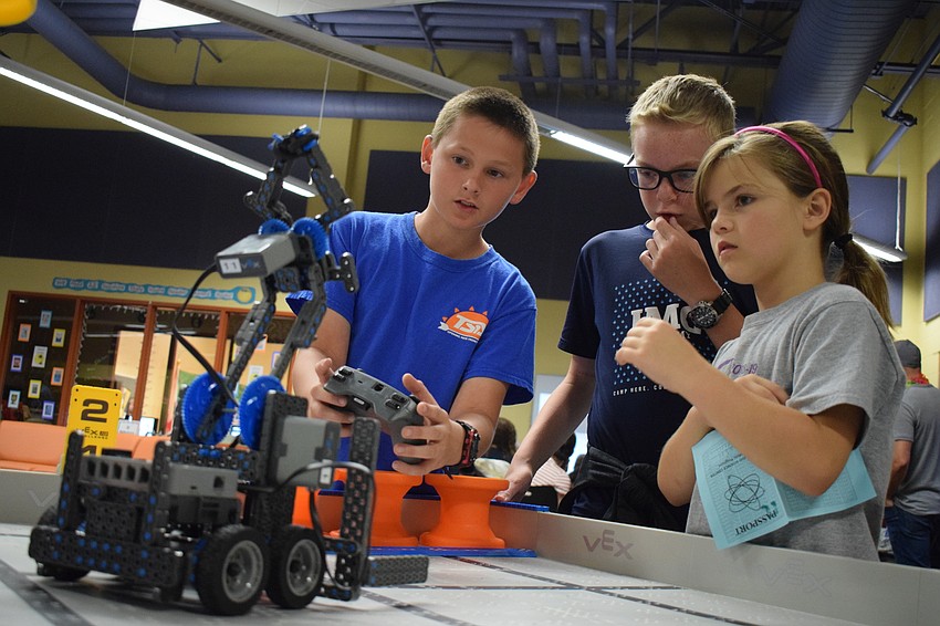Fifth grader Parker Wilson pilots a robot while fifth grader Cameron Locke and third grader Annabell Johnson look on in wonder.