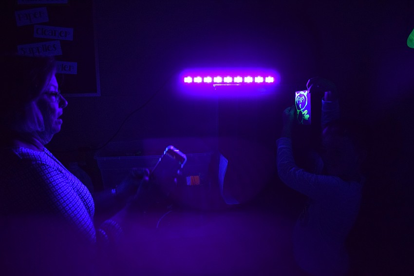 Mary Willis takes a picture of a creation by her son, Jackson Chapman, illuminated by a black light.