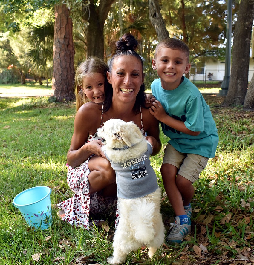 6-year-old Selkie, Amy and 5-year-old Uhtred Garner smile along with their dog Bowser.