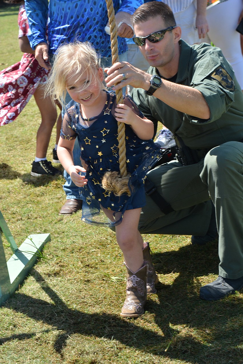 Kodi Rodriguez, 4, gets a little help climbing up a rope and doing a pull-up from Sarasota County Sheriff's Office Dep. Will Rose as she started the sheriff's junior obstacle challenge.