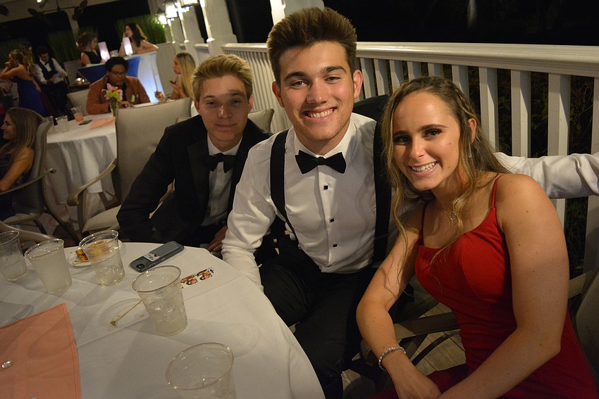 Edward Hamburger, Patrick McFadden and Ava Small relax on the back porch, where there is food, drink and a photo booth.