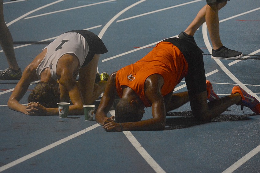 Ben Hartvigsen (1) collapse next to Oviedo's Angel Vicioso after the 4A boys 3200-meter race. They finished second and first, respectively.