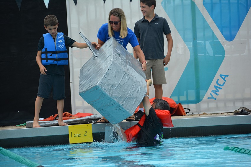 Aaron Ruben tries to bail out his boat before the start as his son, Gullett student Ethan Ruben, watches.