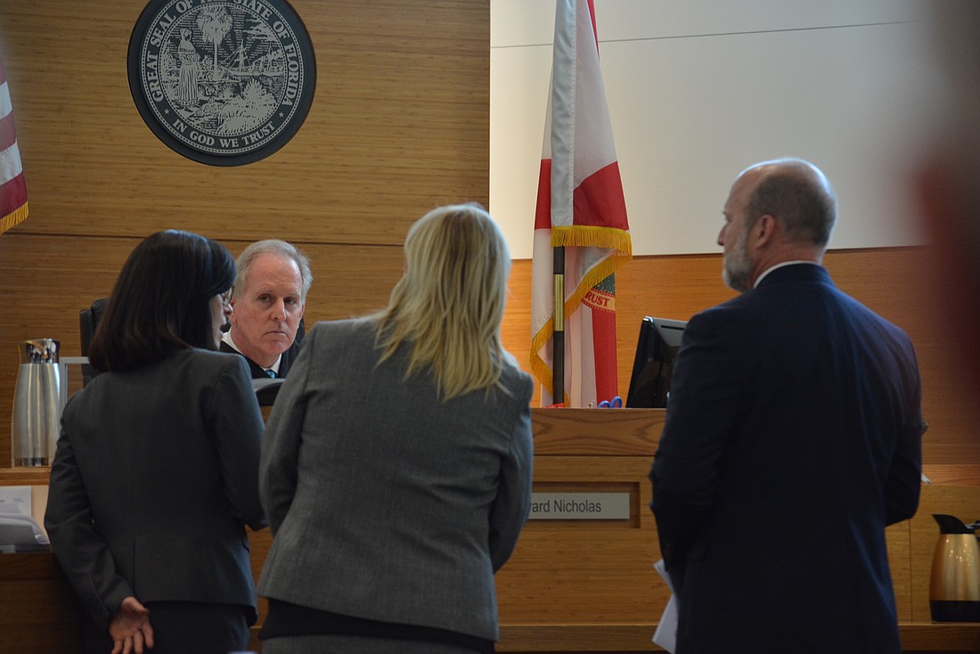 Manatee County 12 Judicial District Circuit Court Judge Edward Nicholas consults with attorneys before ruling to hear more arguments at a later time.