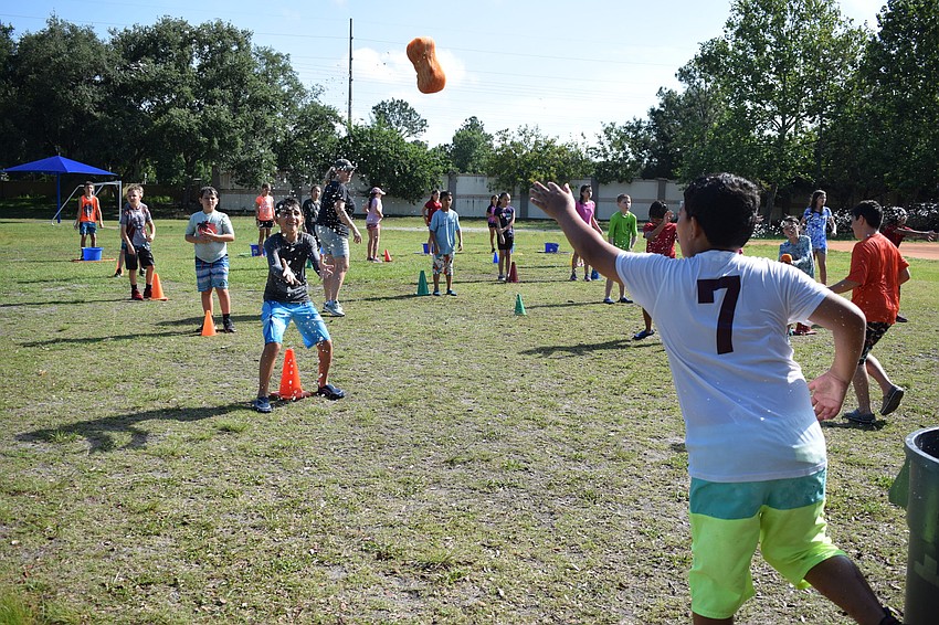 Adrian Echenique tosses a water-logged sponge to Ashton Baron, releasing a spray of water.