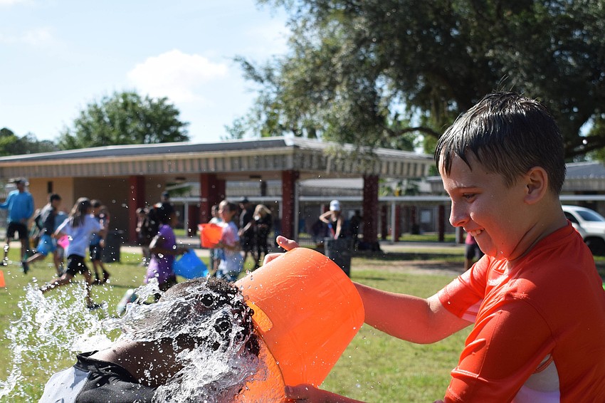 Logan Santiago dumps a bucket of water on Bradyn Boppit's head. Both are in fourth grade.